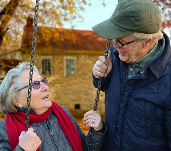 Mor- och farföräldrar på gunga diskuterar videotelefon för pensionsbyn