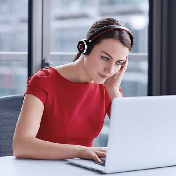 Nainen, joka käyttää kuuloketta, kun se käyttää kannettavaa tietokonetta