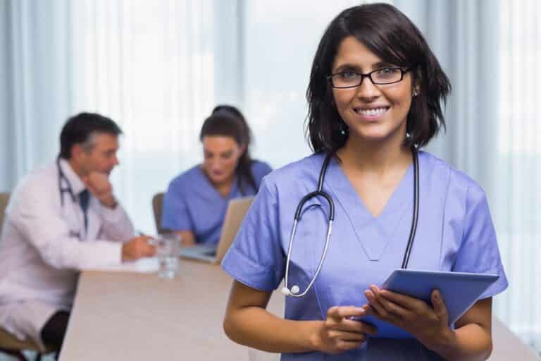 Three medical professionals, one holding a tablet and two consulting