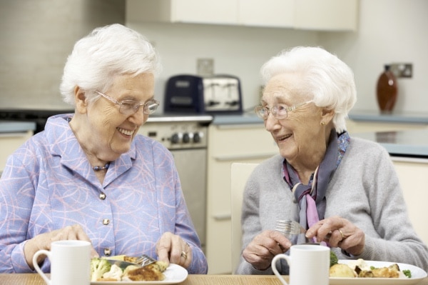 Två äldre kvinnor njuter av sin måltid