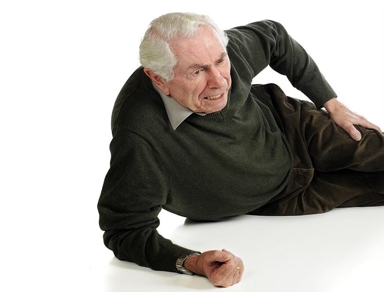 Elderly man who has fallen to the ground, rubbing his sore leg